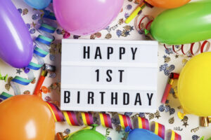 Happy 1st birthday celebration message on a lightbox with balloons and confetti